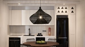 Une cuisine moderne avec des meubles blancs, un réfrigérateur noir, un lave-vaisselle noir et une table de salle à manger ronde, assortie de chaises.