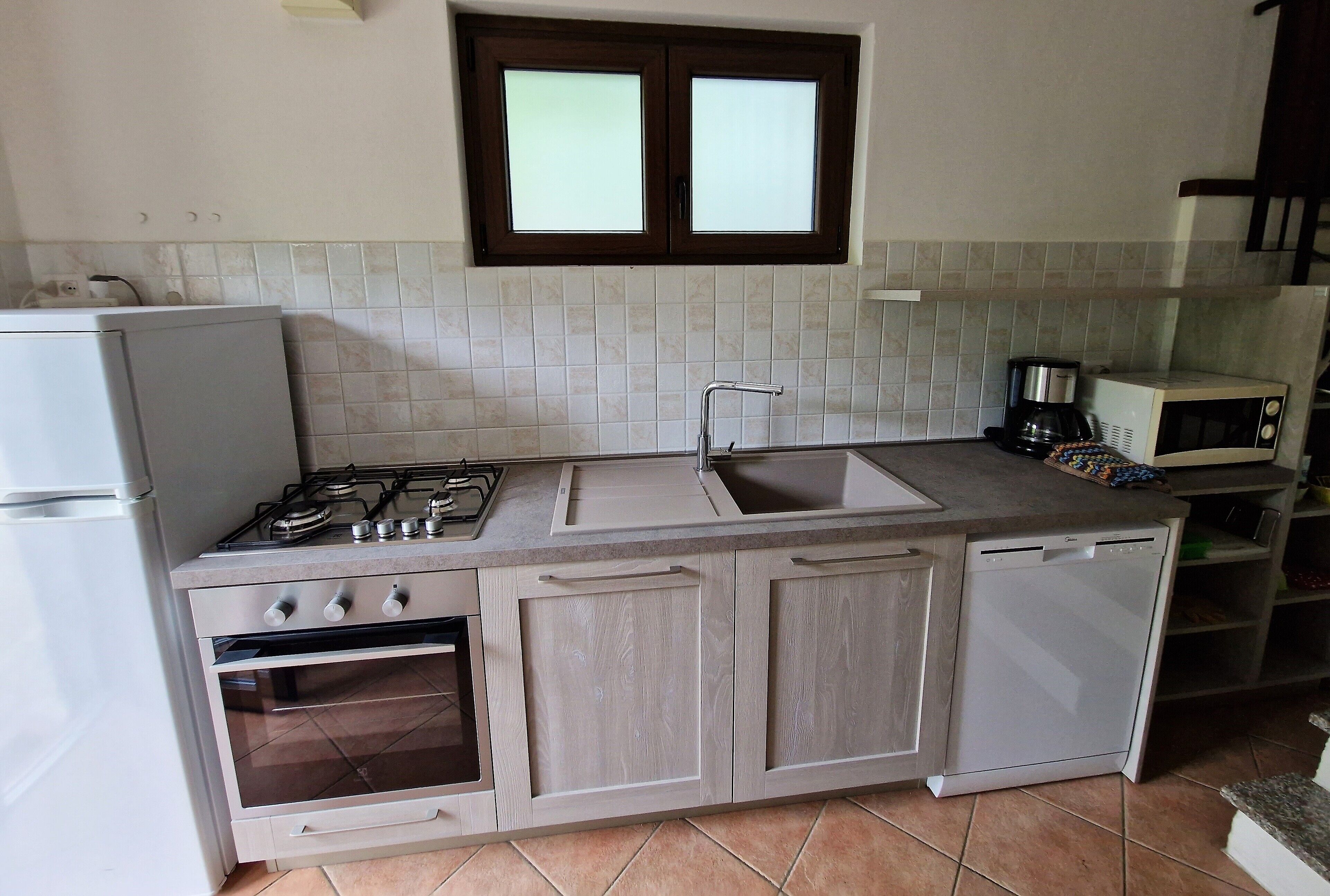 Une cuisine équipée d’une cuisinière à gaz, d’un four, d’un évier et d’un four à micro-ondes.