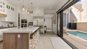 Una cocina moderna con armarios blancos, una isla grande y vista a la piscina.