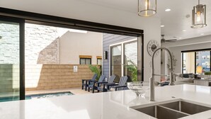 Una cocina moderna con una isla grande, un lavaplatos empotrado y vistas al patio exterior.
