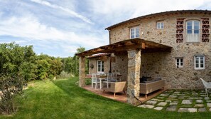 A stone house with a covered patio, outdoor seating, and a well-maintained lawn. - Anticiana 8 (Lucca)