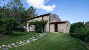 A stone house with a sloped roof, a stone pathway leading to the entrance, and a well-maintained lawn. - Anticiana 8 (Lucca)