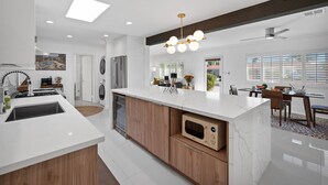 A modern kitchen with a central island, wooden cabinets, and a built-in microwave.