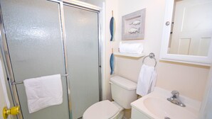Une salle de bain avec une douche à parois de verre, des toilettes, un lavabo et un porte-serviettes.