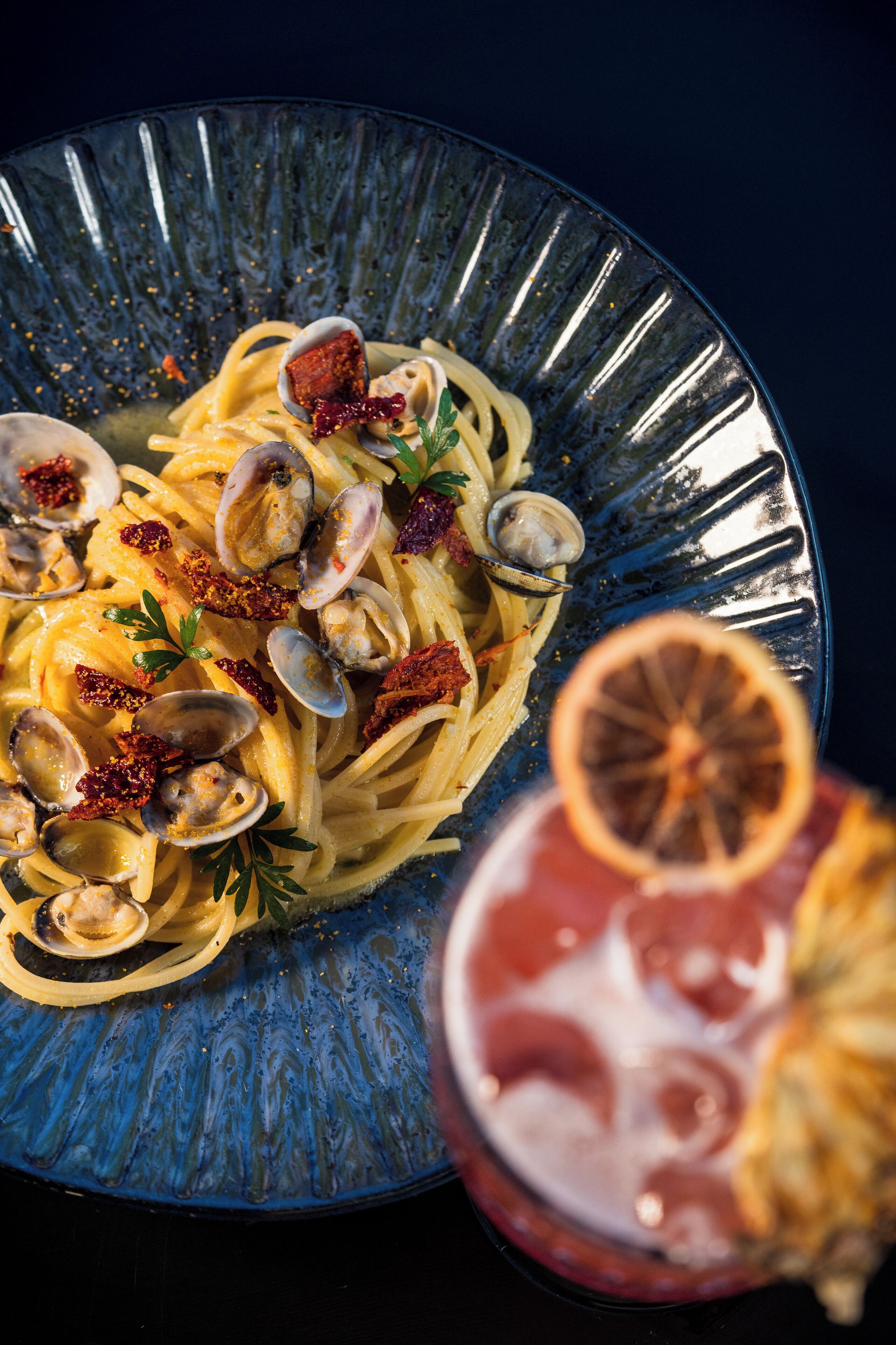 A plate of pasta with clams and lemon garnish.