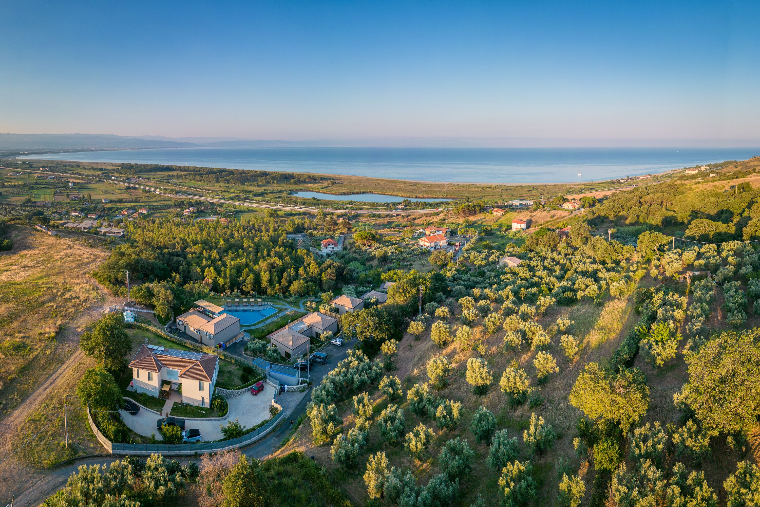 A residential area with houses, a swimming pool, and a view of the sea.