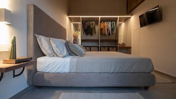 Un dormitorio moderno con una cama grande, armario empotrado, mesita de noche y televisión montada en la pared.