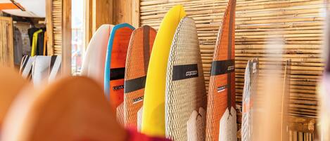 A row of surfboards against a bamboo wall.