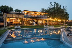 A modern two-story building with a glass facade, a swimming pool, outdoor seating, and string lights. - HANG LOOSE COTTAGE Hotel Resort 4 stelle Gizzeria Calabria (Gizzeria)