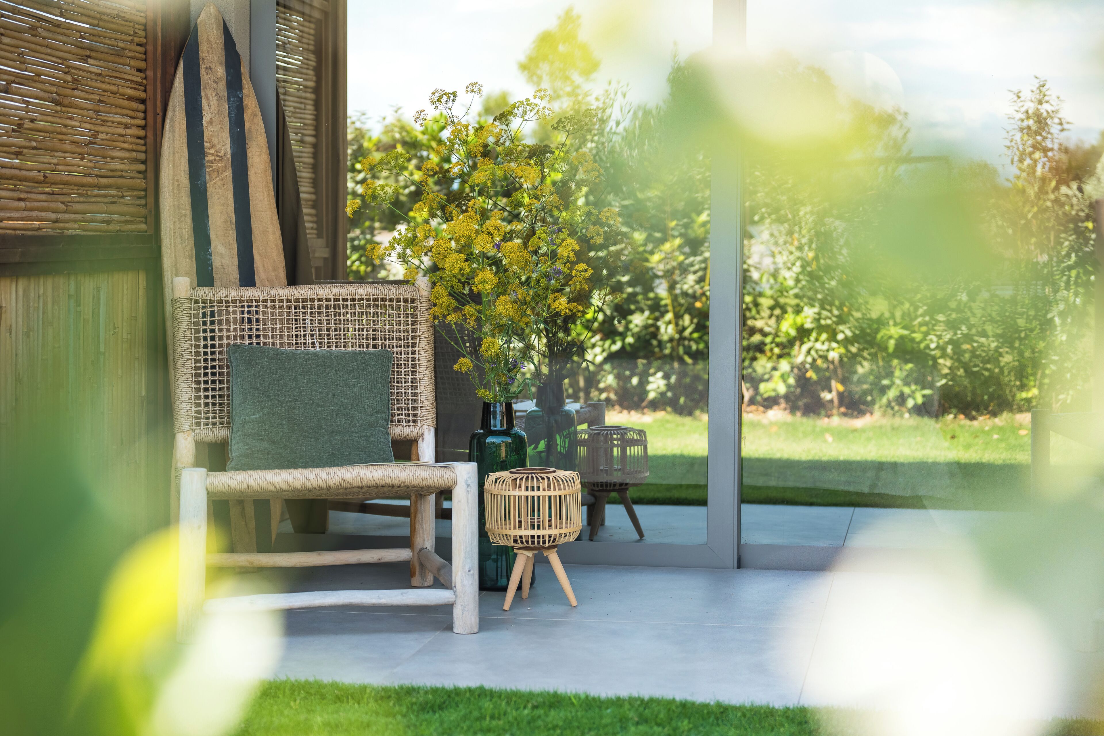 A modern outdoor seating area with wicker furniture and a glass door leading to a garden.