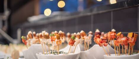 Una serie de cuencos blancos con brochetas de comida, probablemente aperitivos, dispuestas sobre una mesa.