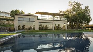 Una casa moderna con ampie vetrate, una piscina e un muro in pietra.