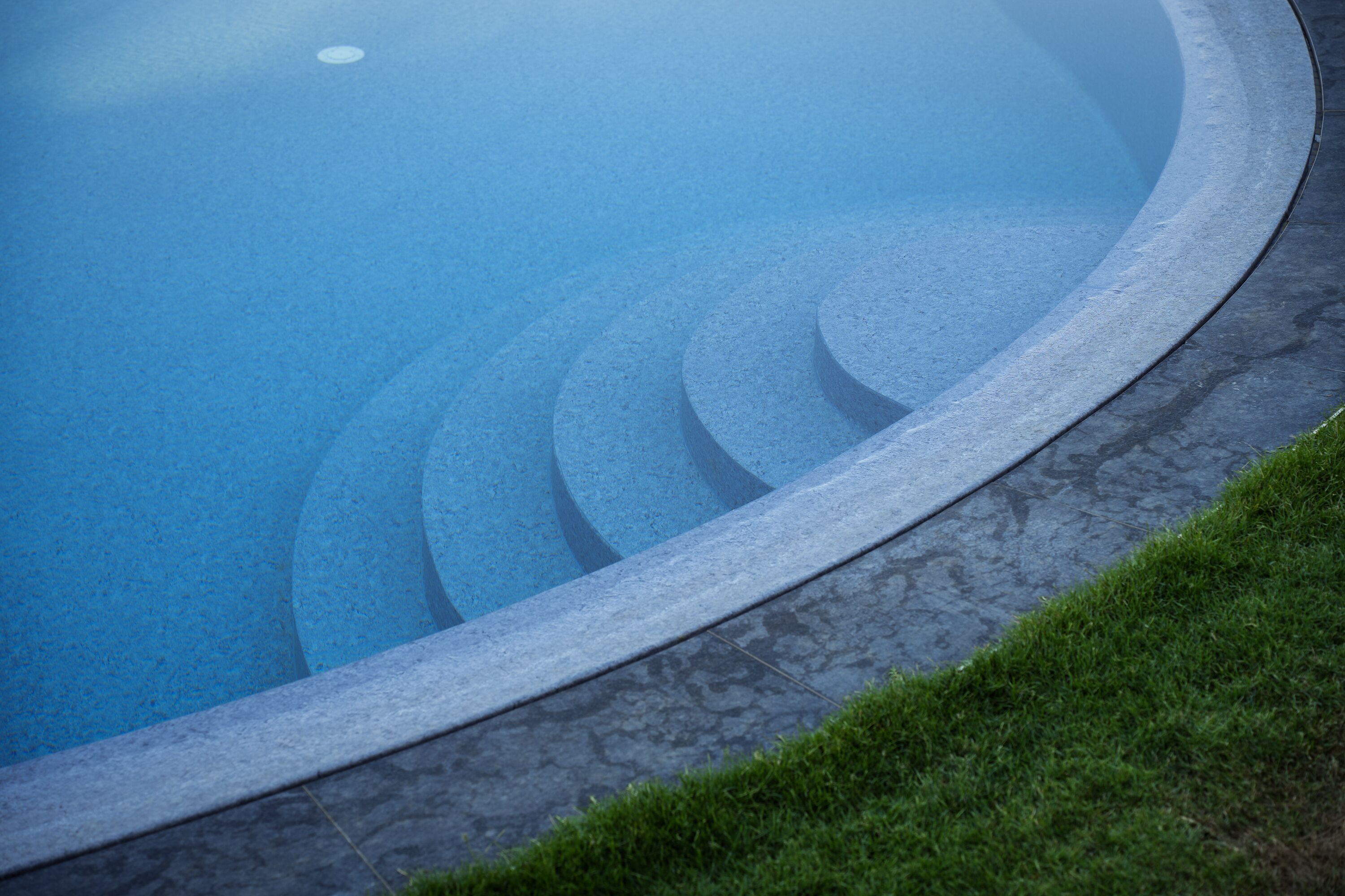 Piscina com borda curva e revestimento de pedra.