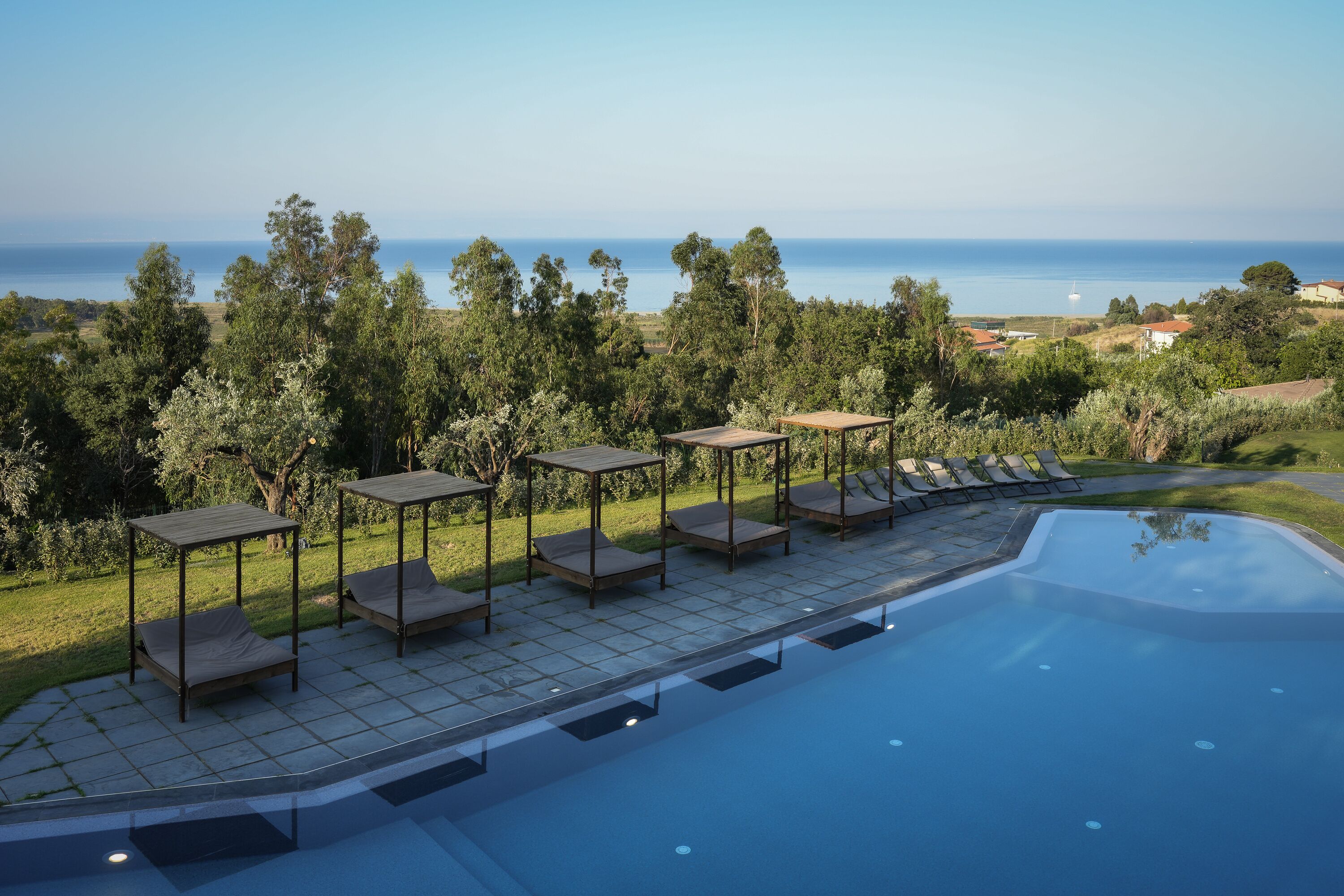 A pool area with lounge chairs and a view of the sea.
