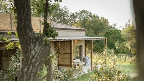A modern house with a covered patio, a wooden fence, and a lush garden.