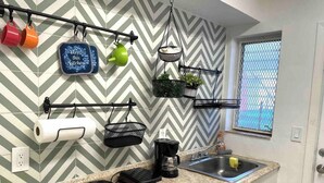 Une cuisine avec un dosseret à motifs en chevron, une machine à café, un évier et une fenêtre donnant sur un beau paysage.