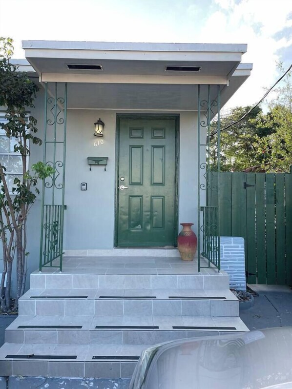 A modern house with a green door, a small porch, and a mailbox.