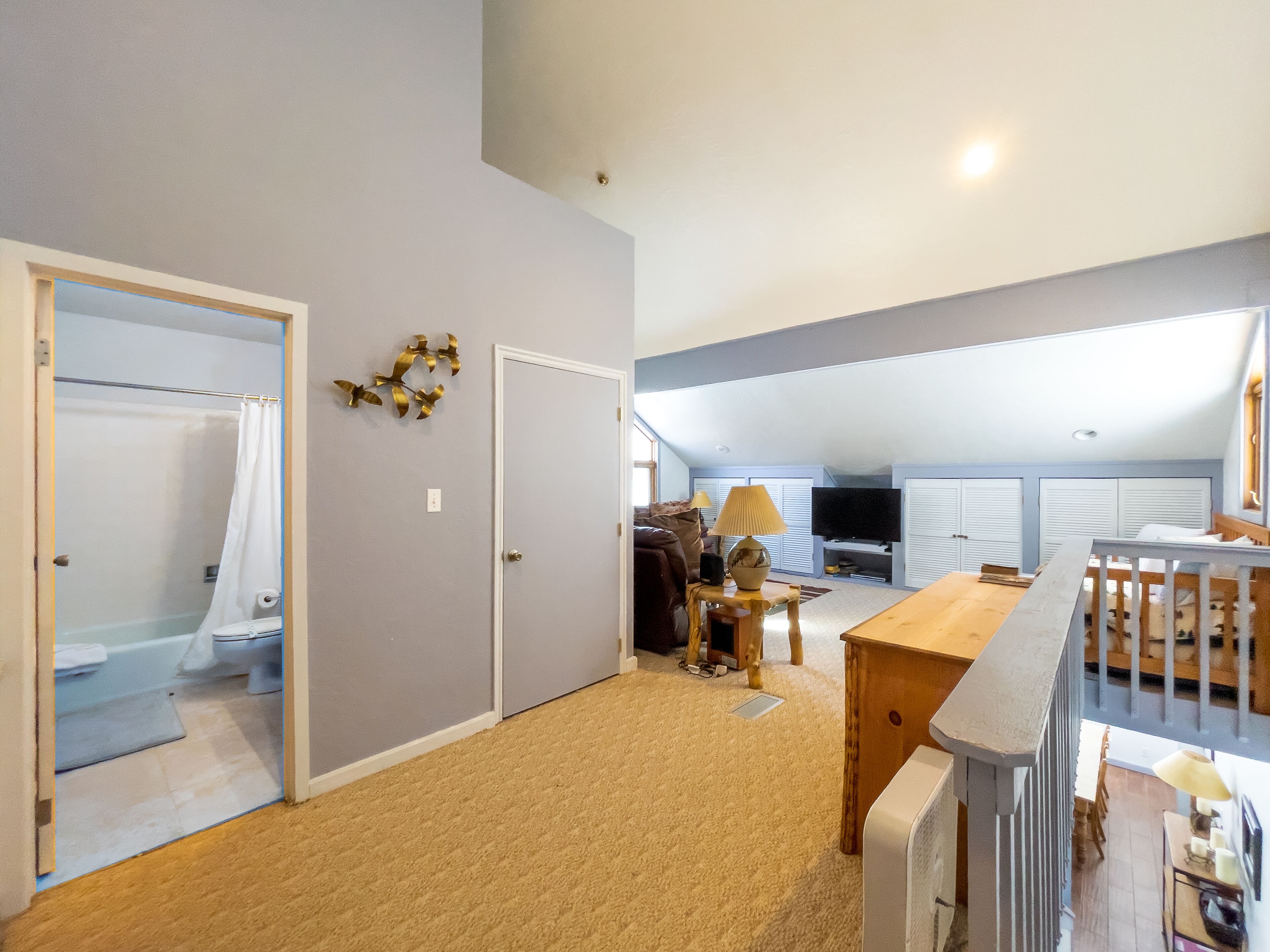 A spacious living area with a high ceiling, a television, and a dining table.