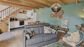 A cozy living room with a grey sofa, a wooden staircase, and a kitchen in the background. - House for 6 rated 3* - Terrace - Guilvinec (Le Guilvinec)