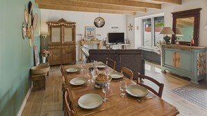 A dining area with a wooden table set for four, a television, and a cabinet with decorative items. - House for 6 rated 3* - Terrace - Guilvinec (Le Guilvinec)