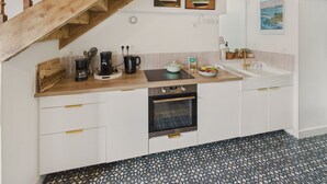 A kitchen with a wooden staircase, a coffee maker, a kettle, a bowl of fruit, and a sink. - House for 6 rated 3* - Terrace - Guilvinec (Le Guilvinec)
