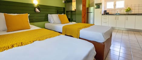 Une chambre d’hôtel avec deux lits, une kitchenette et un mur végétal.