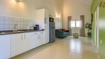 Una cocina moderna con armarios blancos, microondas integrado y cafetera.