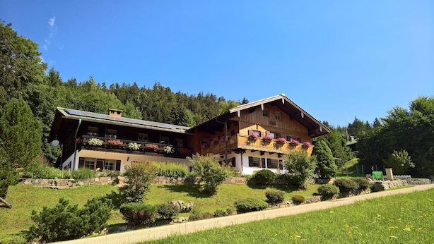 A traditional wooden chalet with multiple balconies, surrounded by lush greenery and a clear blue sky. - Tauernblick vacation apartment - so close to heaven! Maria- Gern, 4 stars. (Berchtesgaden)