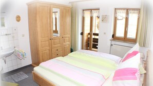 A bedroom with a bed, wooden wardrobe, and a window. - Tauernblick vacation apartment - so close to heaven! Maria- Gern, 4 stars. (Berchtesgaden)