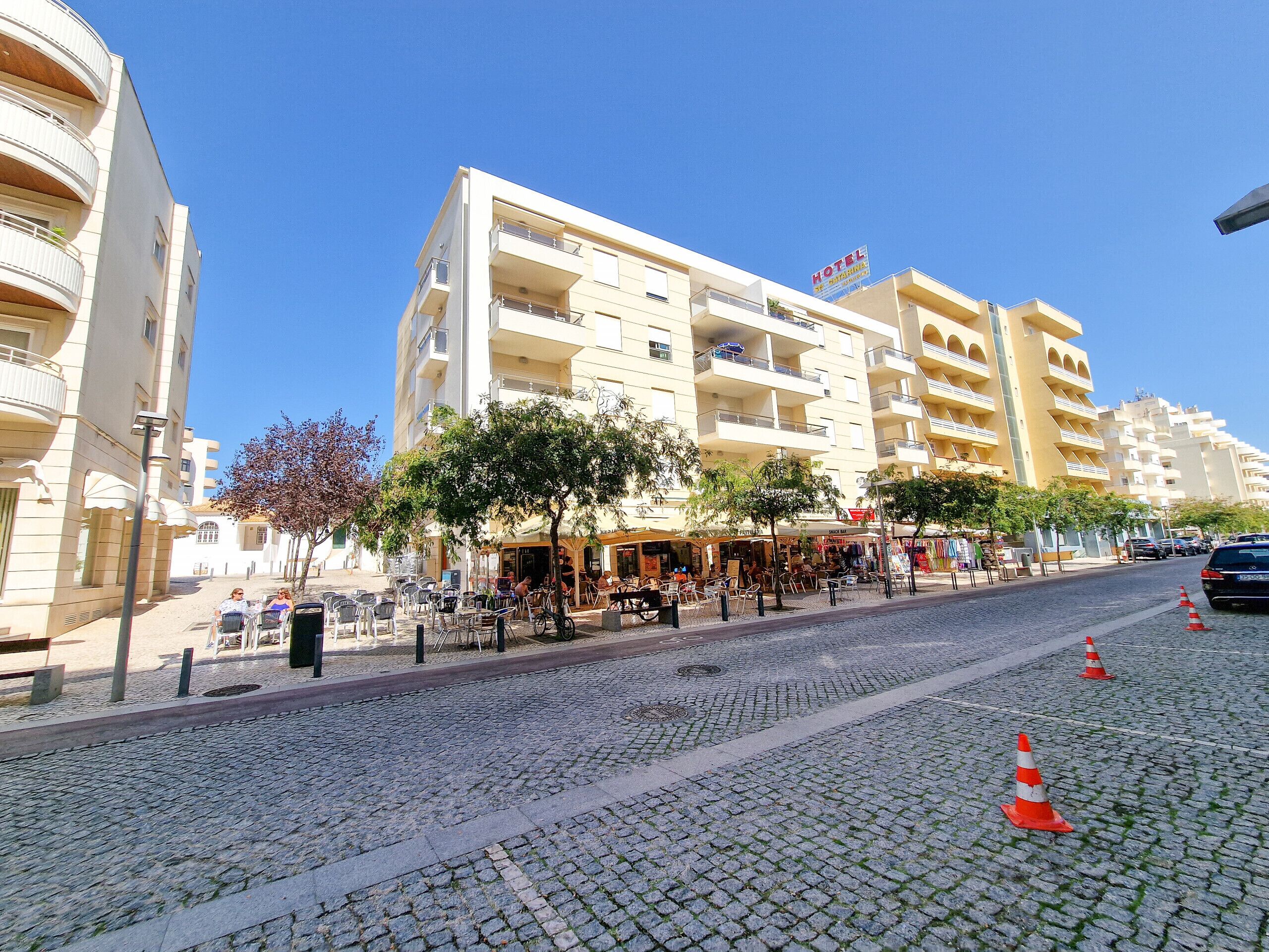A hotel with multiple floors, outdoor seating, and a cobblestone street.