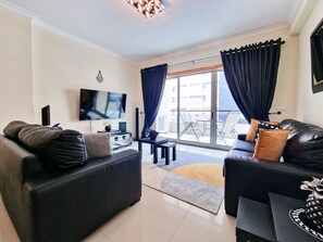 A modern living room with a flat-screen TV, two sofas, a coffee table, and a dining area with a table and chairs.