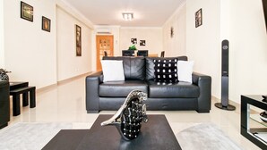 A modern living room with a black leather sofa, a black coffee table with a decorative sculpture, and a black floor lamp.