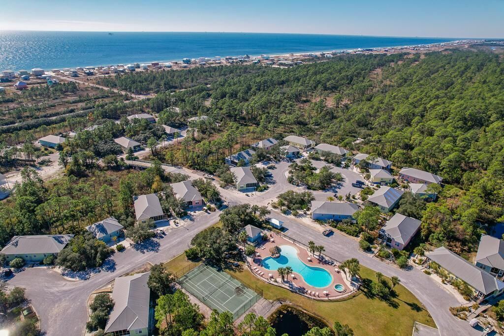 An aerial view of a residential area with houses, a swimming pool, and a tennis court.
