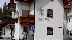 Ein zweistöckiges Gebäude mit roten Ziegeldach, hölzernen Balkonen und einem Schild mit der Aufschrift 'Haus Bagci', das es als Ferienwohnung kennzeichnet.