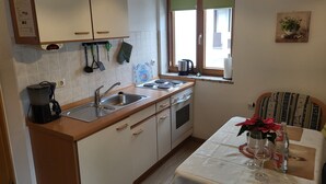Eine kleine Küche mit Spüle, Herd und Fenster mit Jalousien.