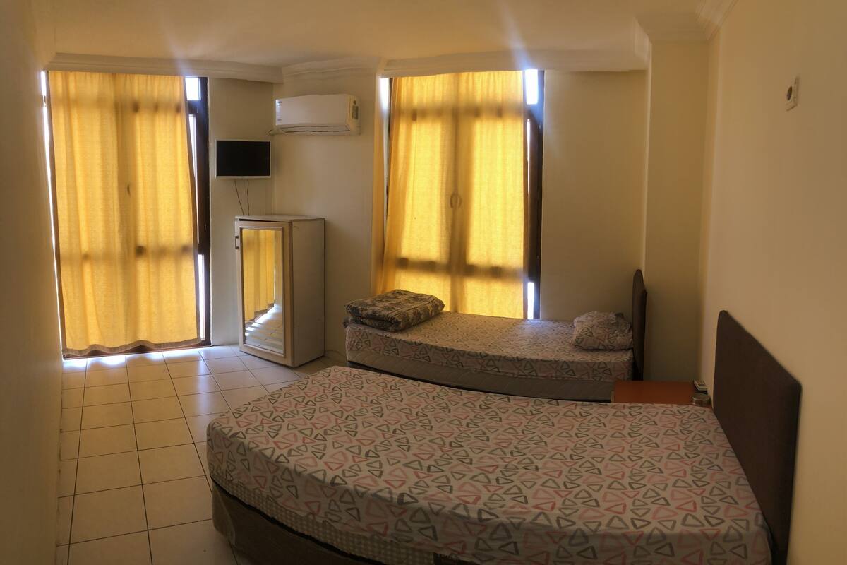 A room with two beds, a television, and an air conditioning unit.