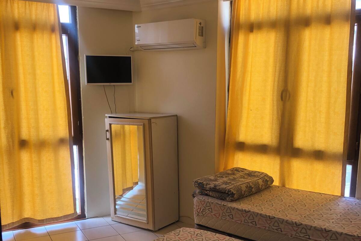 A room with two beds, a TV, and an air conditioner.