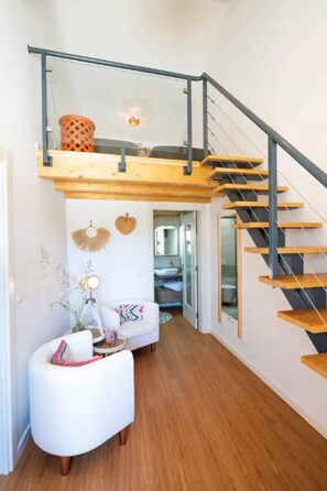 A modern interior with a wooden staircase, a white sofa, and a ceiling light fixture.