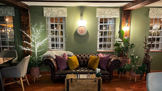 Un salon chaleureux avec un canapé en cuir, une table basse en bois et des murs verts.
