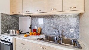 A kitchen with granite countertops, stainless steel appliances, and wooden cabinets. - Gkountis Deluxe Apartment: Sea View, Shared Pool & Wi-Fi (Lefkadas)