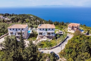 Ein Küsteneigentum mit mehreren Gebäuden, einem Swimmingpool und Meerblick.