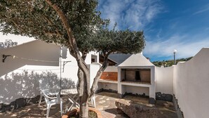 A patio area with stone flooring, a tree, outdoor furniture, and a barbecue grill. - Holiday Home "Sottotorre 2" close to the Sea with Private Garden & A/C (Calasetta)