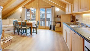 Un interno accogliente in legno con zona pranzo, angolo cottura e vista sulle montagne.