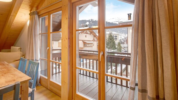 Un interno in legno con un balcone, ampie finestre e un tavolo con sedie.