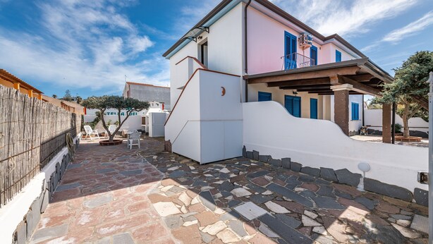 A building with a stone-paved courtyard, a white exterior, and blue shutters.