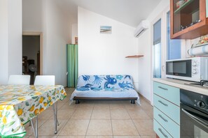 Une pièce de taille modeste comprenant un lit, une table à manger, un coin cuisine et une petite fenêtre.