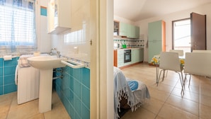 A kitchen with a sink, cabinets, and a dining area with chairs.