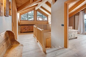 Een houten interieur met een slaapkamer op een vide, een houten bank en een trap.