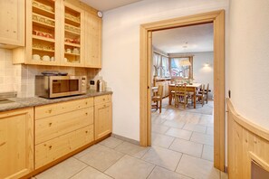A kitchen with wooden cabinets, a microwave, and a dining area with a table and chairs.