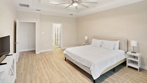 Ein Schlafzimmer mit einem Bett, einem Deckenventilator, einem Fernsehschrank und einem Nachttisch mit einer Lampe.